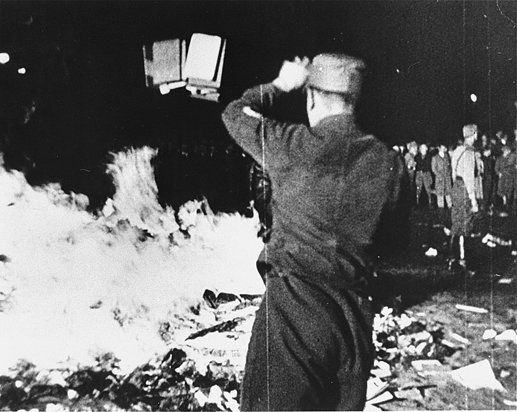 Photograph of a member of the SA throws confiscated books into the bonfire during the public burning of "un-German" books on the Opernplatz in Berlin.